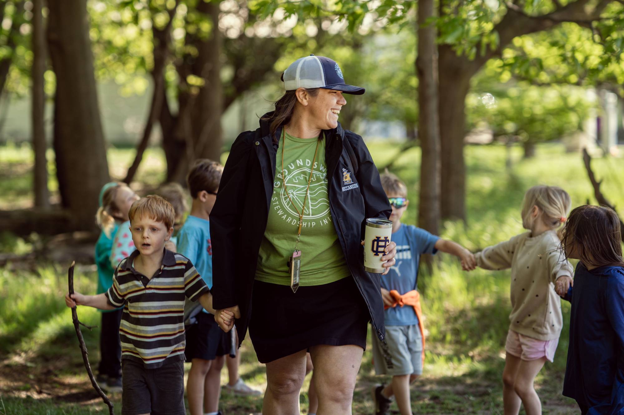 adult leading a group of young children on a walk through the woods